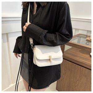 Détail d'un sac bandoulière blanc en cuir avec un fermoir métallique doré rectangulaire