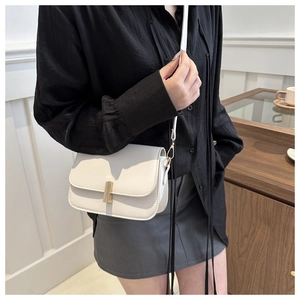 Gros plan d'un sac à bandoulière blanc vintage avec boucle métallique dorée chic