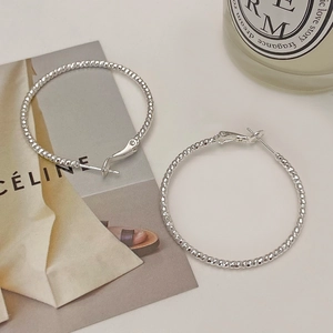 Detail shot of silver hoop earrings with bead texture on minimalist magazine background
