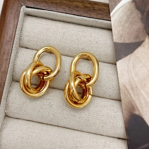 Detail of interlocking gold multi-loop geometric earrings with a polished finish