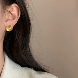 Elegant gold orchid flower stud earrings with brushed metal texture worn by a model