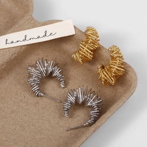 Macro detail of French vintage C-shape earrings with gold and silver wire-wrapped design