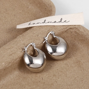 Macro view of polished silver teardrop earrings with a sleek mirror finish on a natural tray