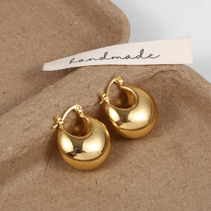 Macro shot of gold puffy hoop earrings with a mirror-polished finish on a rustic tray
