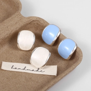 Detail of white marble and sky blue enamel stud earrings with silver borders in a tray