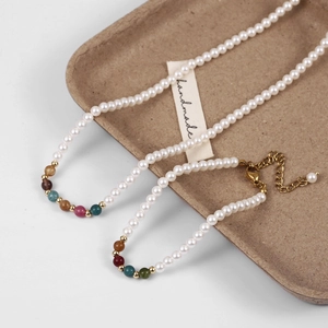 Detail of handmade pearl jewelry set with colorful natural stones and golden clasps