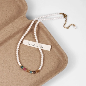 Detail of handmade pearl necklace showing colorful beads and golden lobster clasp closure