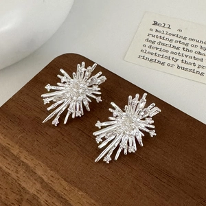 Elegant starburst stud earrings with brilliant zircon stones on vintage wood background