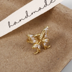 Detail shot of a gold butterfly ear cuff with sparkling zircon on a brown handmade box