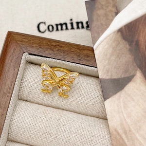 Close-up of golden bow-tie ear cuff with marquise-cut zircons on a wooden jewelry box