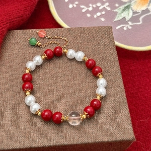 Close-up of red agate and pearl beads with gold accents on jewelry display