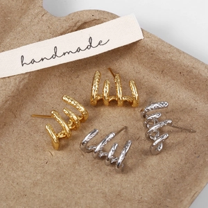 Détail de boucles d'oreilles quatre griffes or et argent avec texture à pois martelés