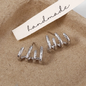 Gros plan des boucles d'oreilles argentées à quatre griffes avec texture sur emballage