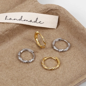 Detail of twisted cable hoop earrings with micro-set zircon in gold and silver finish