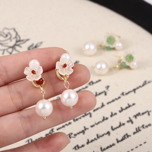 Dettaglio di orecchini di perle a fiori con pietra rossa e finitura dorata in stile retrò