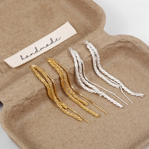 Macro detail of gold and silver tassel earrings with a shimmering frosted metal finish