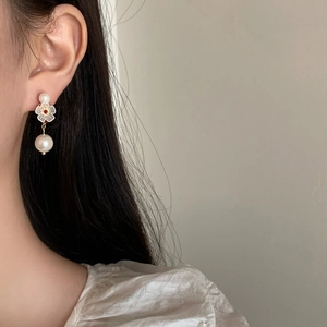 Orecchini pendenti con perle e fiore bianco con strass rosso su modella donna