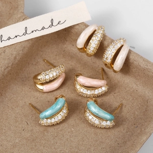 Close-up of three pairs of vintage enamel hoop earrings with zircons in a paper gift box