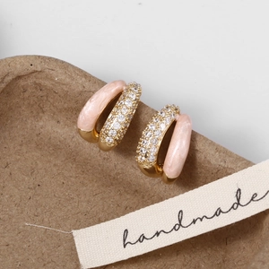 Detail of gold C-shaped earrings with pink enamel marble and sparkling zircons