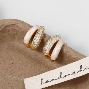 Detail of vintage French gold earrings with white enamel and cubic zirconia stones