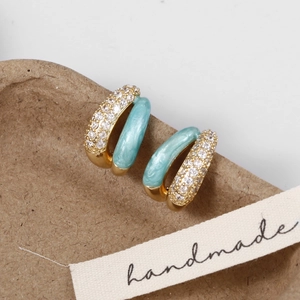 Macro detail of C-shaped earrings with blue marble enamel and sparkling zircons