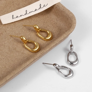 Macro detail of irregular oval stud earrings in polished gold and silver finishes
