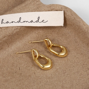 Close-up of golden polished chain link drop earrings on a handmade paper tray