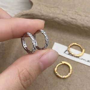 Twisted hoop earrings with inlaid zircons in gold and silver finishes for women