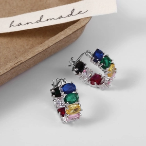 Macro detail of silver-finish hoop earrings featuring multi-colored oval zircon stones