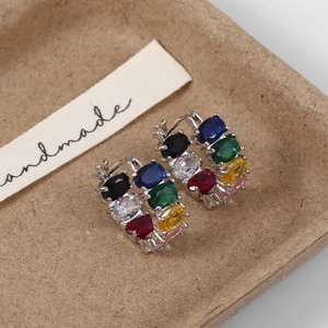 Detail view of silver C-shaped hoop earrings with multi-color oval cut gemstones