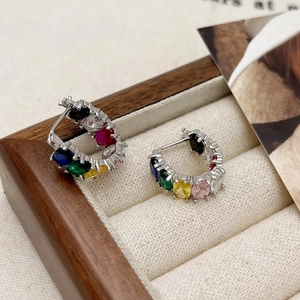 Macro shot of silver C-shaped hoop earrings with vibrant colorful cubic zirconia inlay