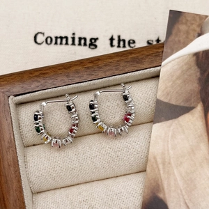 U-shaped silver earrings with colorful gemstones in a beige velvet jewelry box