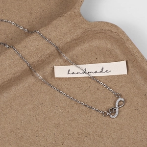 Vue détaillée d'un collier cœur infini serti de cristaux blancs sur plateau rustique