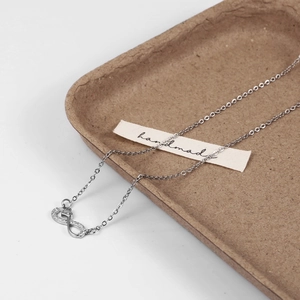 Gros plan du collier signe infini avec cœur en zircon sur un plateau fait main