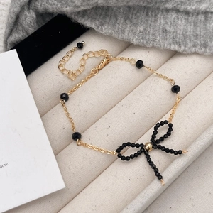 Bracciale vintage dorato con perline nere sfaccettate e ciondolo a fiocco per donna elegante