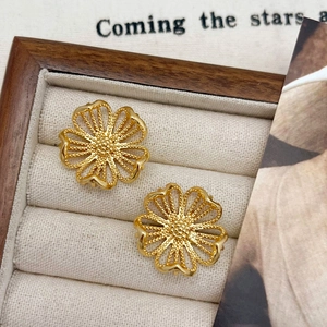 Detailed view of hollow floral gold earrings with beaded edges on a jewelry box liner
