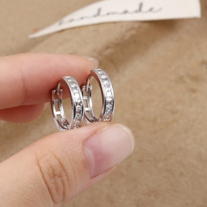 Close-up of silver hoop earrings with sparkling cubic zirconia on brown texture