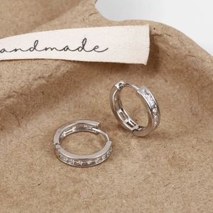 Close-up of silver hoop earrings with sparkling cubic zirconia on a handmade paper base