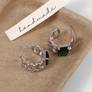 Detailed macro of vintage silver chain earrings with emerald square-cut zircon stones