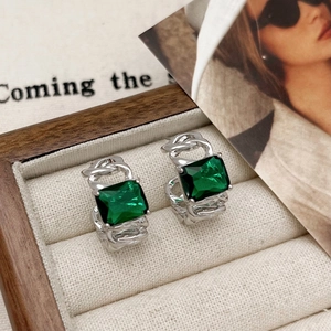 Detail of vintage silver earrings with square emerald green zircon in a jewelry box