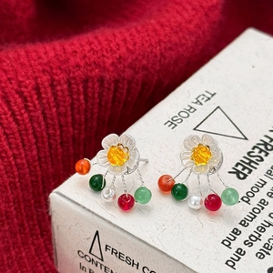 Handcrafted floral pearl earrings with colorful beads on a red knit background