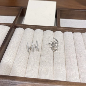 Detailed view of silver triple-row zircon stud earrings on a wooden jewelry display