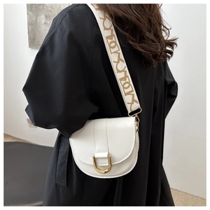 Detail of white saddle bag with golden U-shaped buckle and geometric patterned strap
