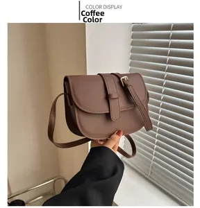 Detailed close-up of a brown leather saddle bag with a golden adjustable buckle strap
