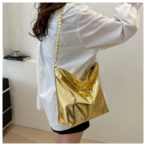 Close-up of metallic gold tote bag with chain strap worn by a model in casual style