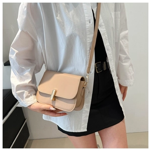 Detail of beige square crossbody bag with gold metallic buckle on a model wearing white shirt