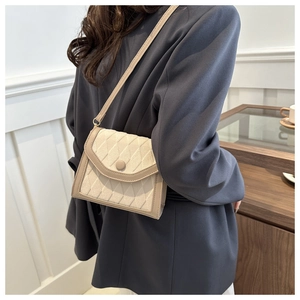 Detail of Korean style beige quilted crossbody bag with flap closure and round button