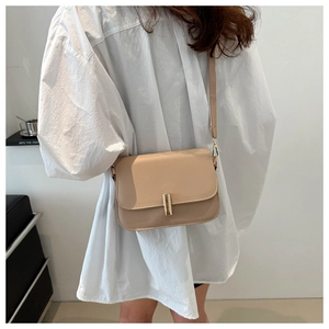 Detail of minimalist beige crossbody bag featuring a sleek gold rectangular metal clasp