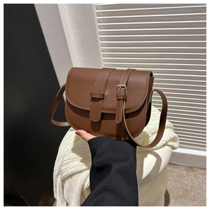 Detail view of brown vintage saddle bag featuring matte leather and gold buckle accents