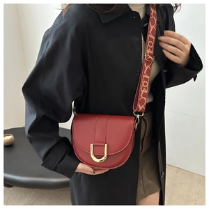 Detail of red saddle bag with gold metal buckle and patterned jacquard strap